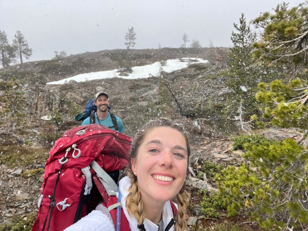 Two hikers a man and a woman caught in a snowstorm. They are still smiling